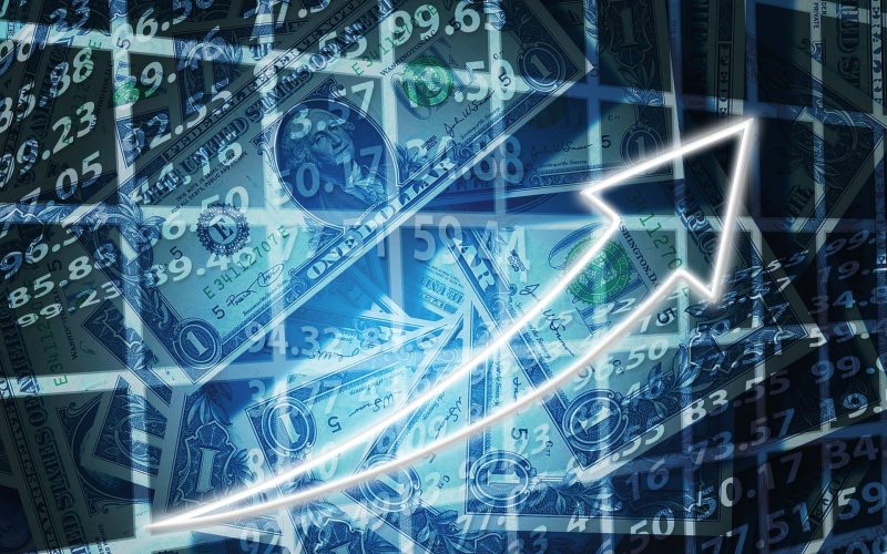 Steigender Pfeil vor Dollarbanknoten und Börsenzahlen