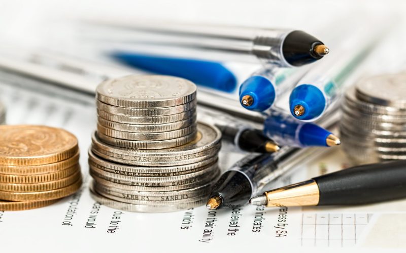 Münzstapel und Stifte auf Finanzunterlagen